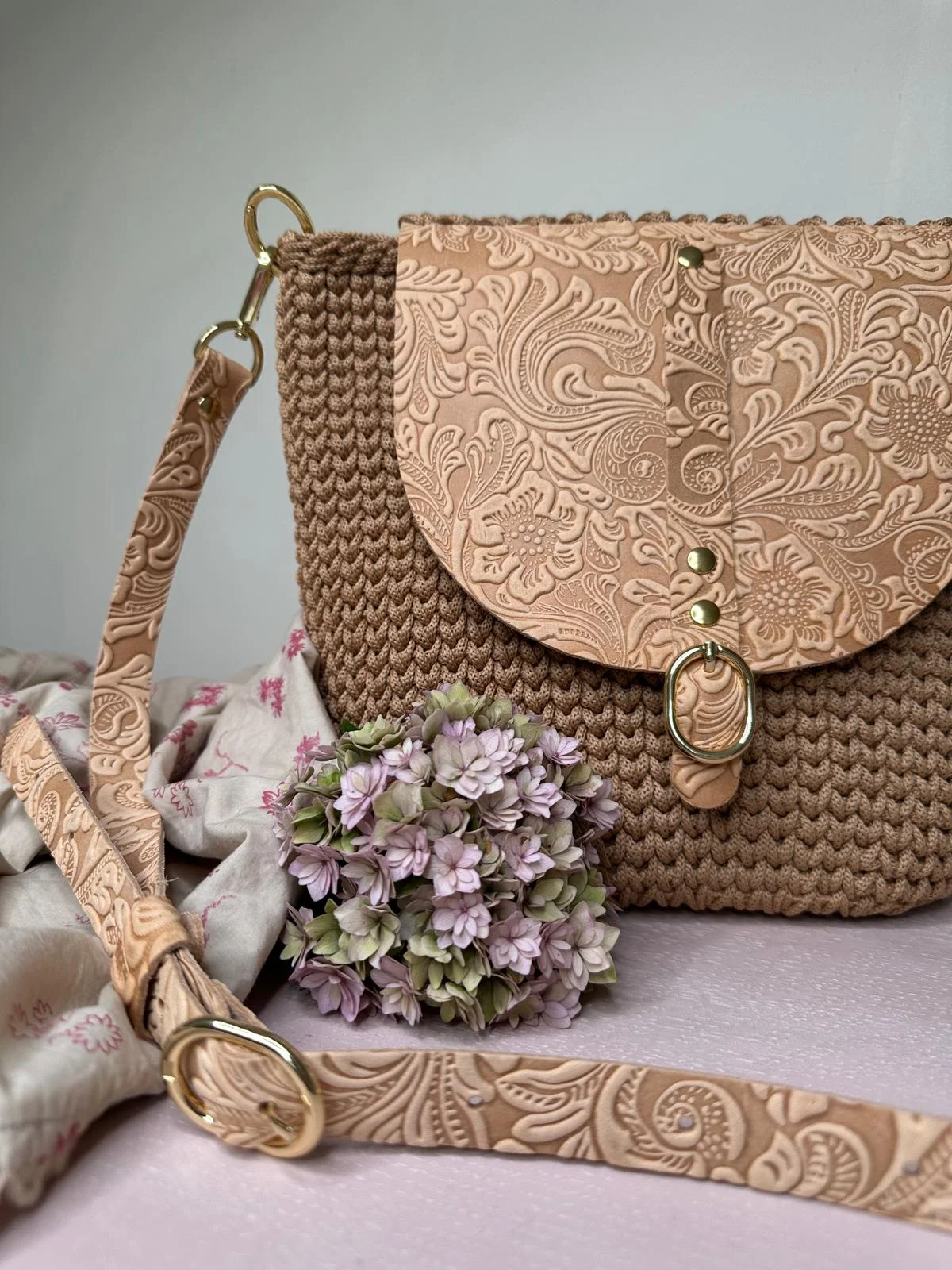 Naturfarbene Häkeltasche mit floral geprägtem Naturleder-Deckel und goldenem Verschluss, dekoriert mit getrockneter Hortensie